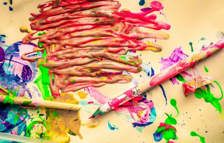 Zwei Pinsel, jede Menge bunte Farbe auf hellem Papier