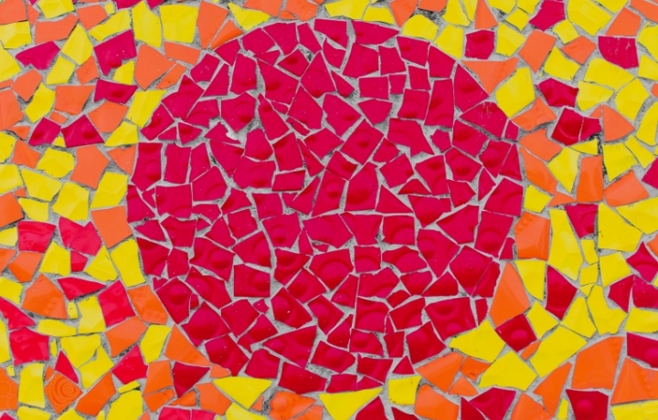 Mosaikbild mit rotem Kreis in der Mitte und gelben und orangefarbenen Steinen drum herum.