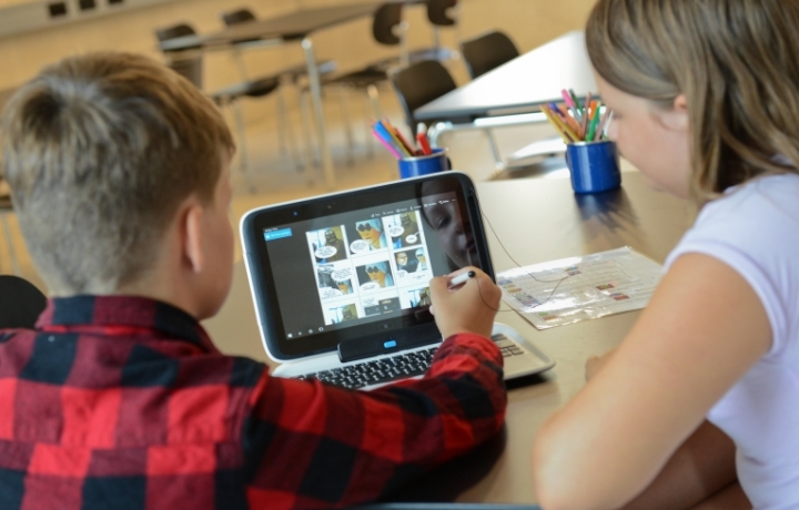 Zwei Kinder erstellen am Laptop einen Comic