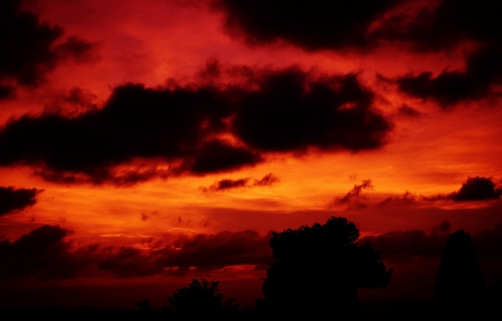 Blutroter Himmel, wirkt bedrohlich. Wolken nur als Silhouetten zu sehen.