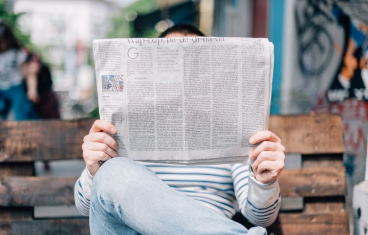 Ein Mann hält eine Zeitung hoch und liest.