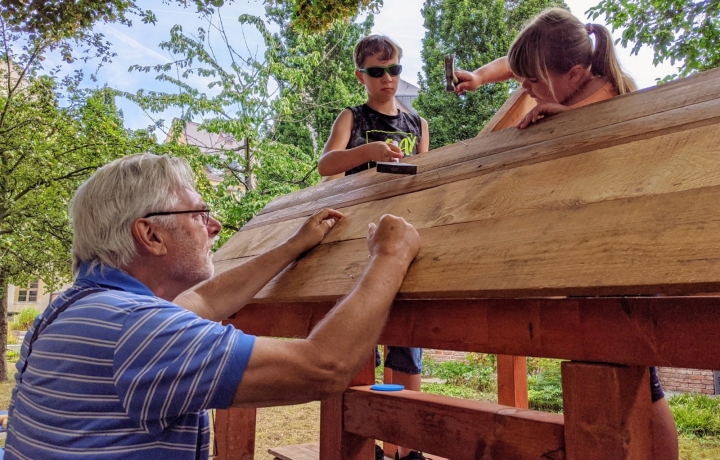 Zwei Kinder bauen unter Anleitung ein Fachwerkhaus
