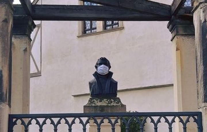 Statue Luthers mit Maske vor dem Geburtshaus in Eisleben